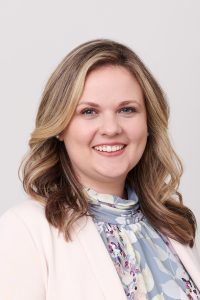 Miller Kaplan partner, Kelly Pollard, facing camera, smiling, on light grey background.