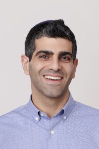 Miller Kaplan partner, Liel Shemtov, facing camera, smiling, on light grey background.